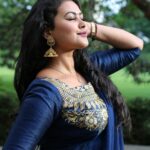 Portrait of a woman in traditional blue and gold attire, posing outdoors.