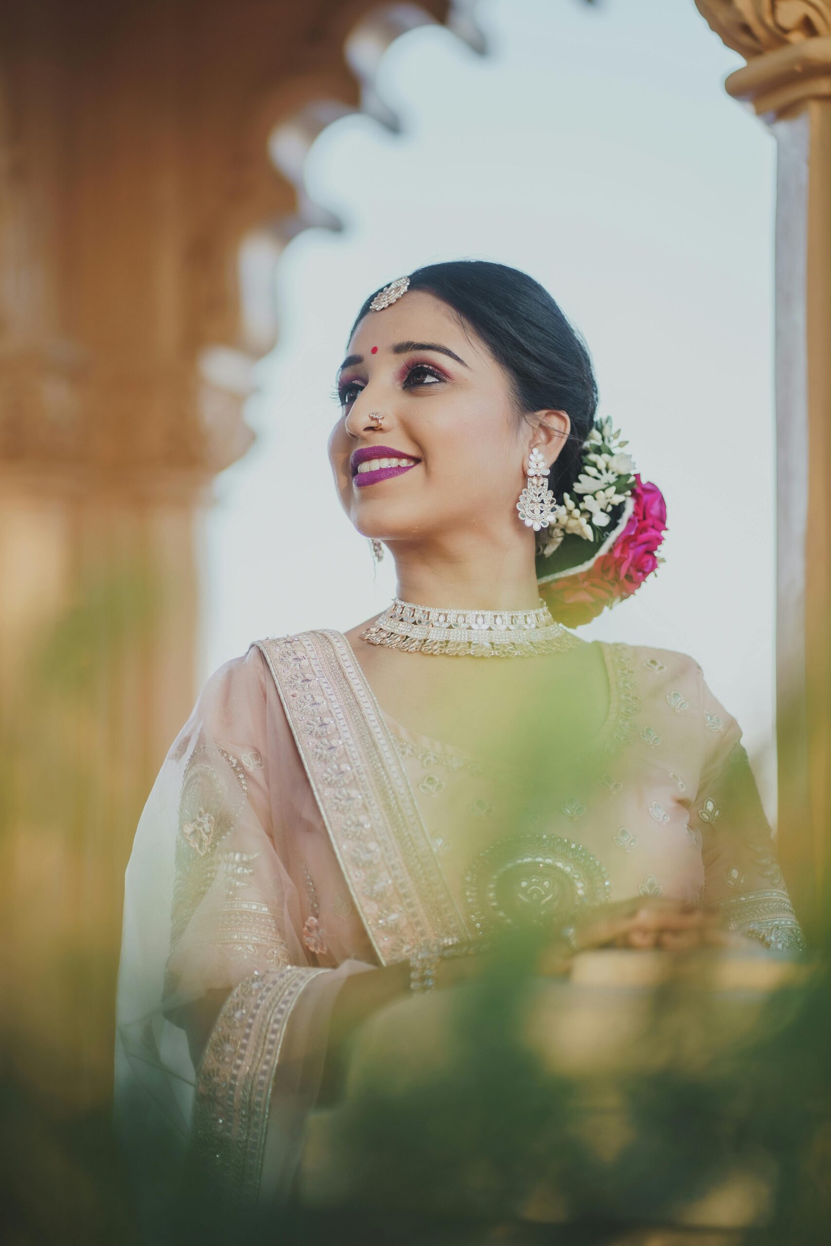 A beautiful Indian bride in traditional attire, adorned with jewellery, smiling on her wedding day.